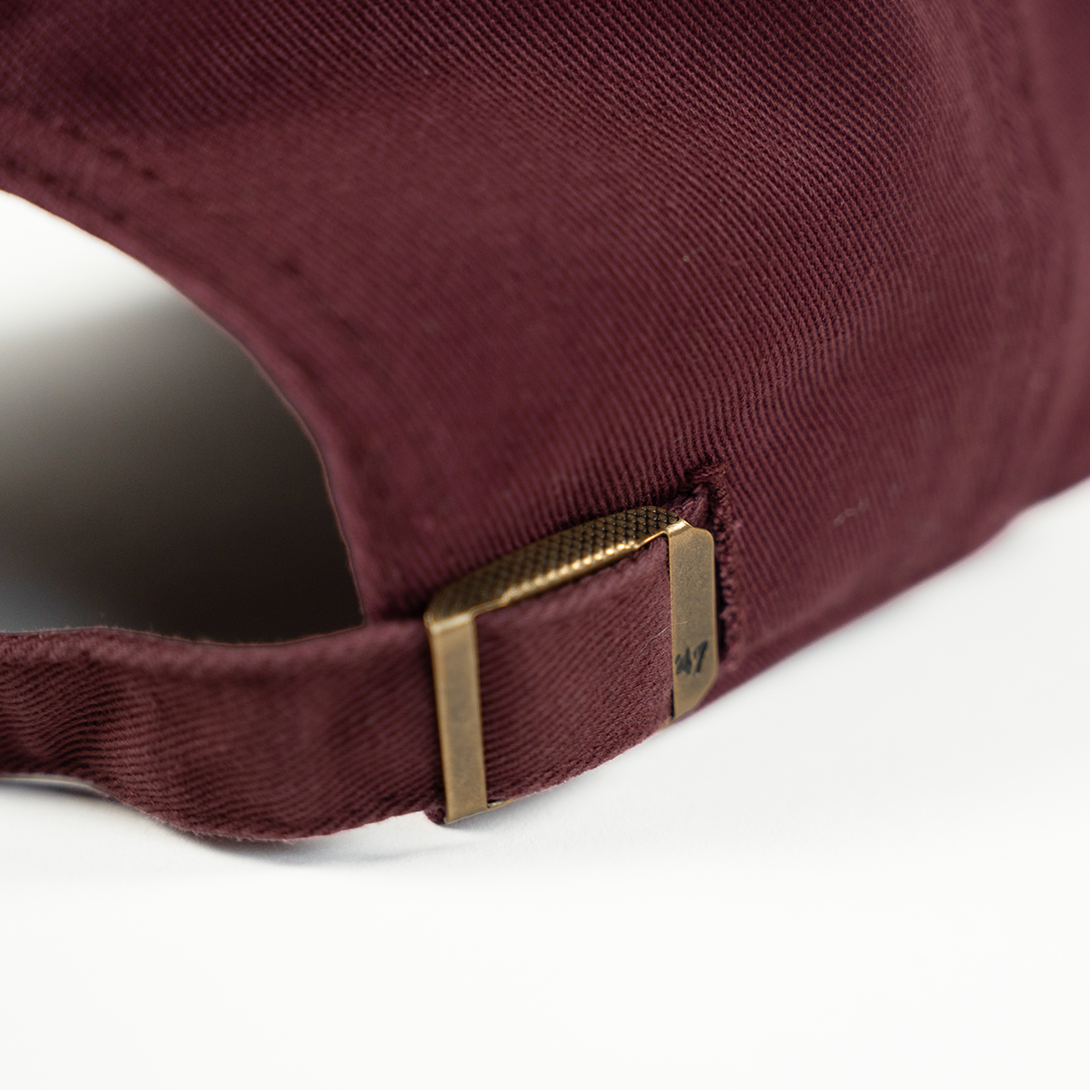 Close-up of a maroon cap with a gold buckle on a white background
