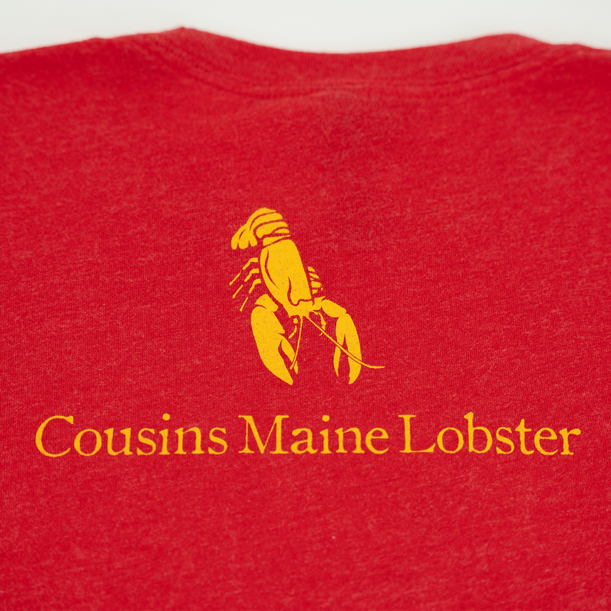 Red shirt with yellow 'Cousins Maine Lobster' logo