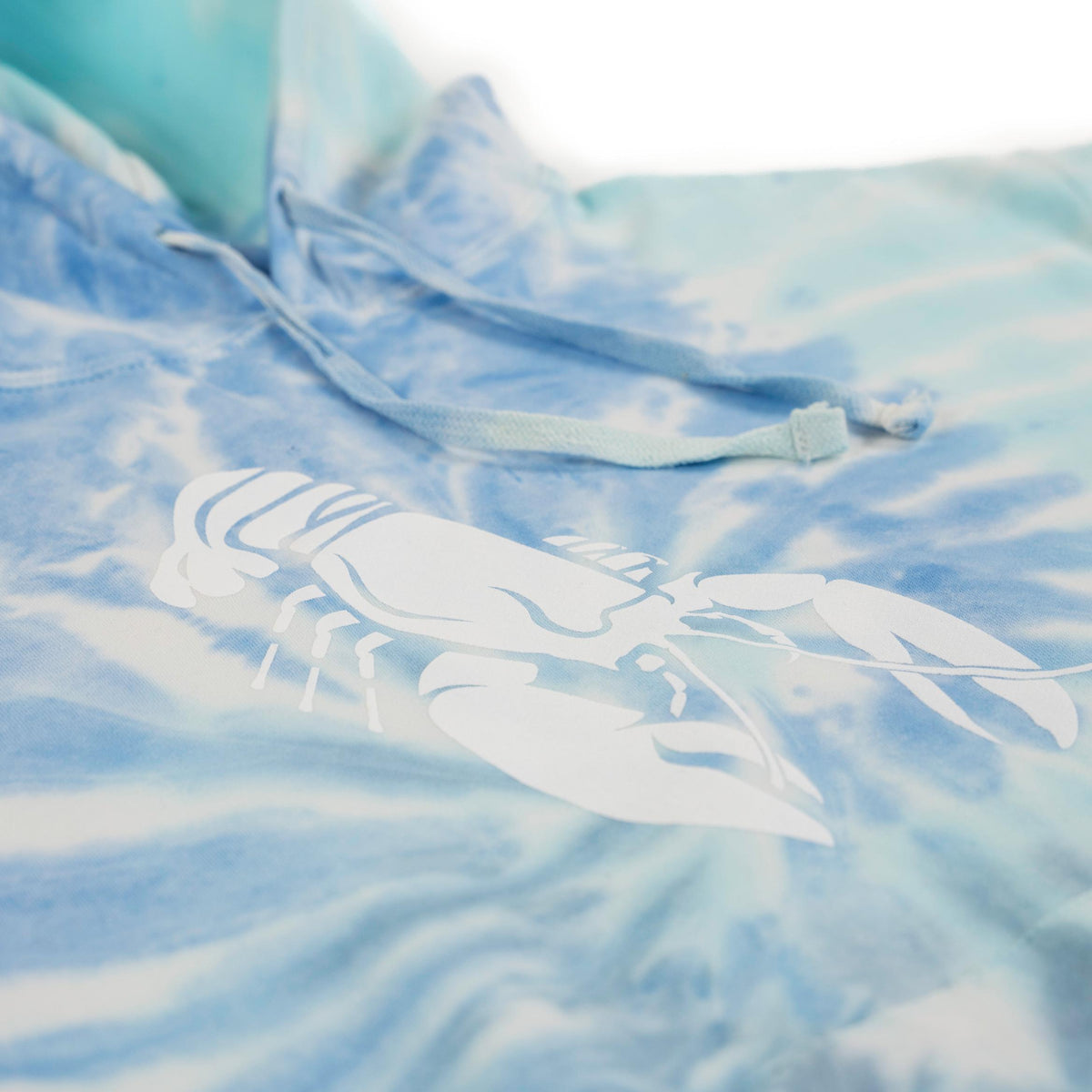 Low-angle view of blue tie-dye hoodie with drawstrings and a large white lobster graphic