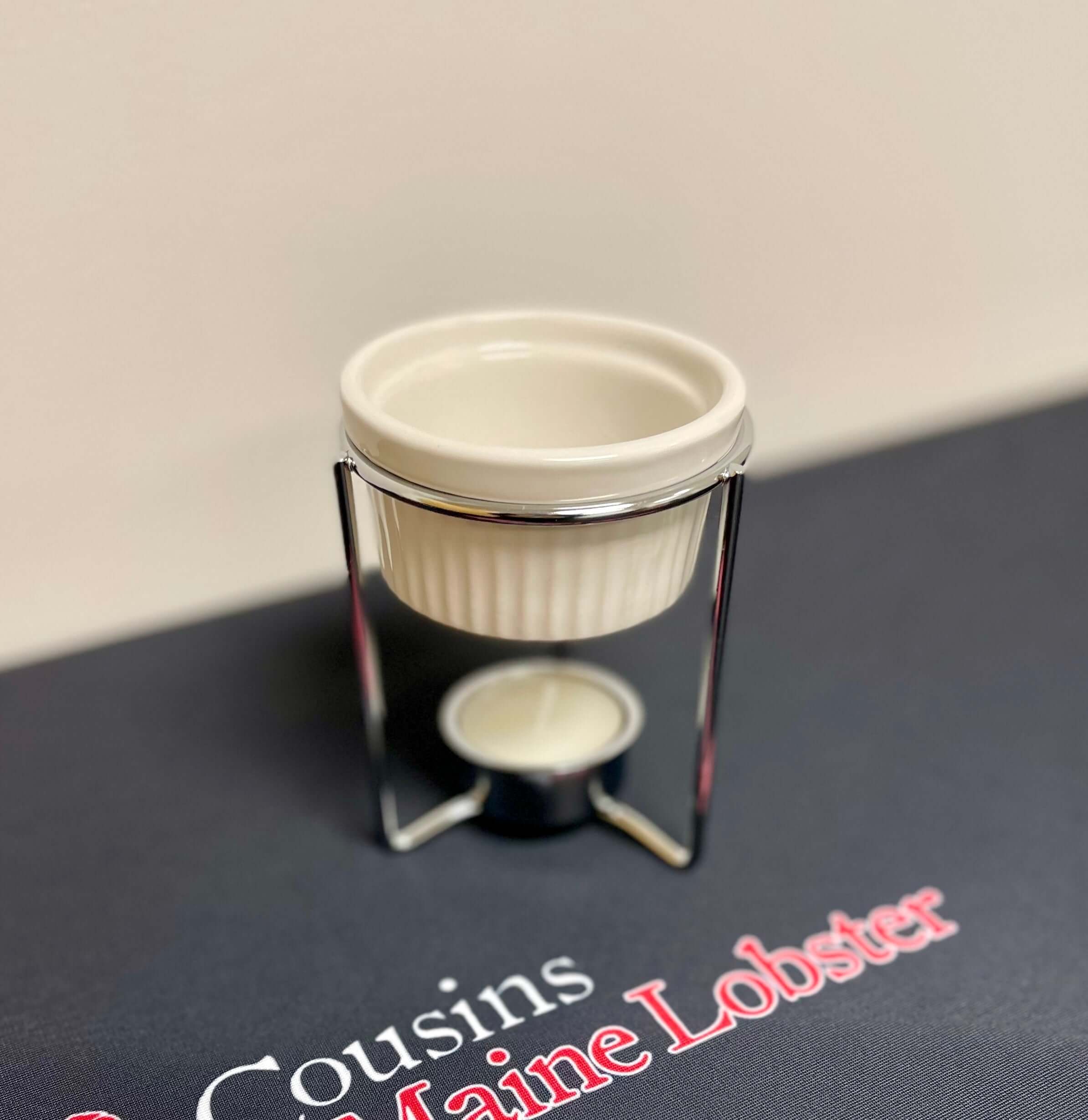 Small white butter warmer, on a dark surface with 'Cousins Maine Lobster' branding.