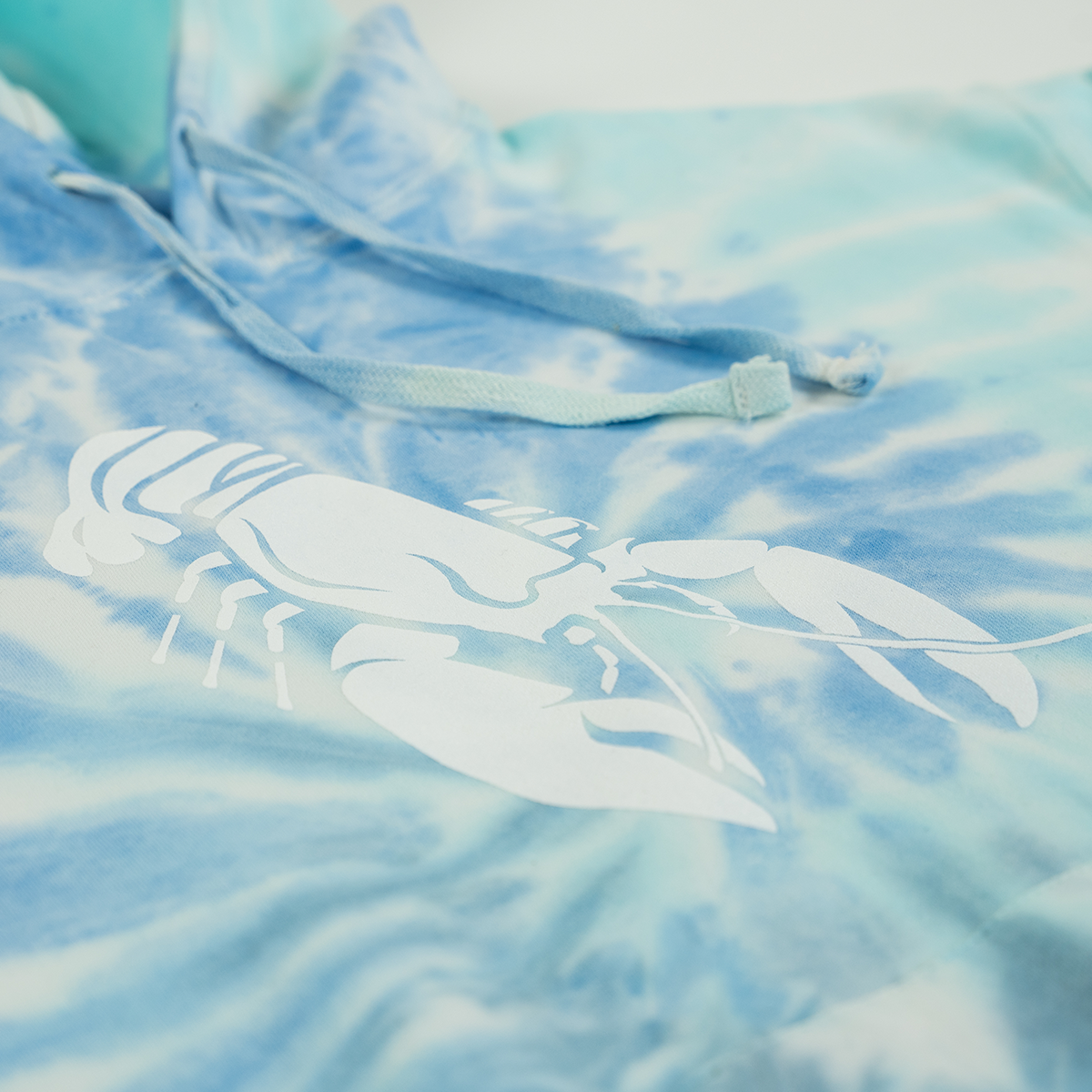 Tie-dye hoodie with a white lobster design on a light blue and white background