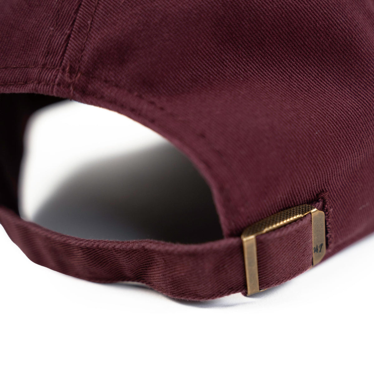 Close-up of dark maroon dad hat adjustable strap with antique brass slide buckle closure